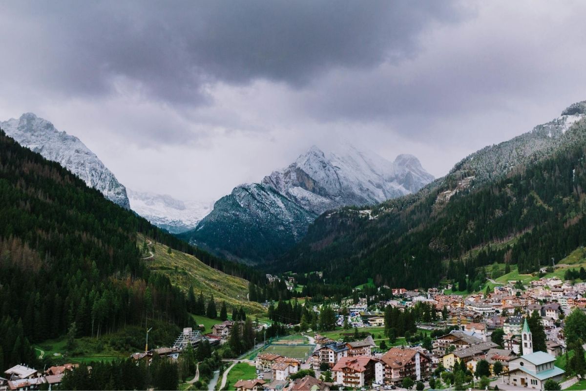 Vista panoramica di Canazei con le Dolomiti sullo sfondo, ideale per rappresentare la cultura e le tradizioni locali.