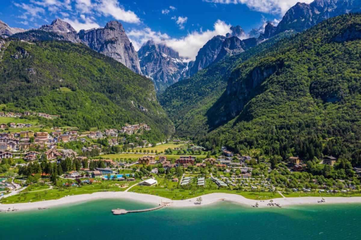 Vista panoramica del Lago di Molveno con bambini che giocano sulla spiaggia